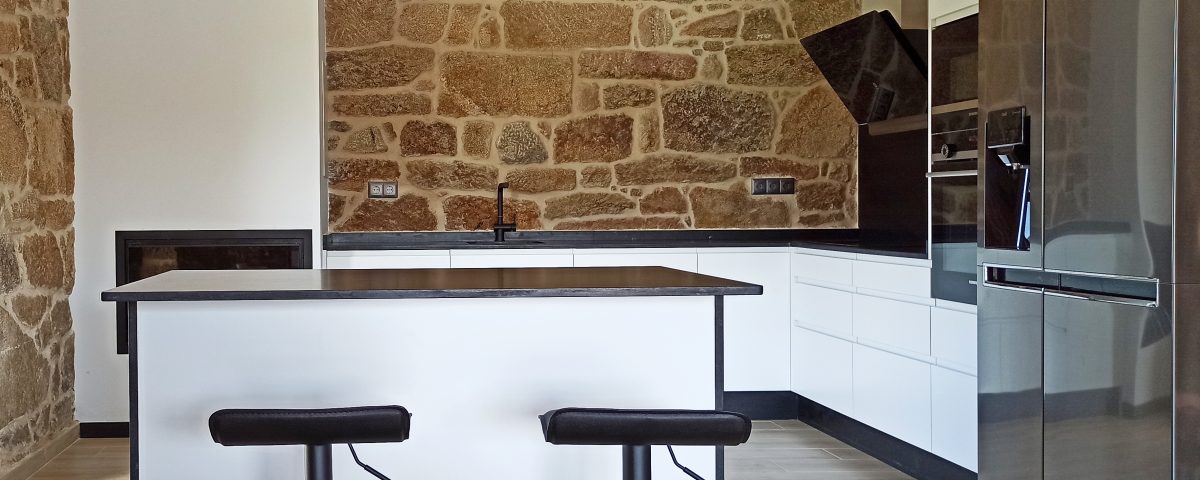 Cocina en blanco y negro con pared de piedra