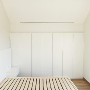 Dormitorio con somier, mesitas de noche y armario en blanco