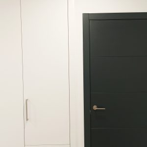 Puerta negra en habitación blanca con armario blanco