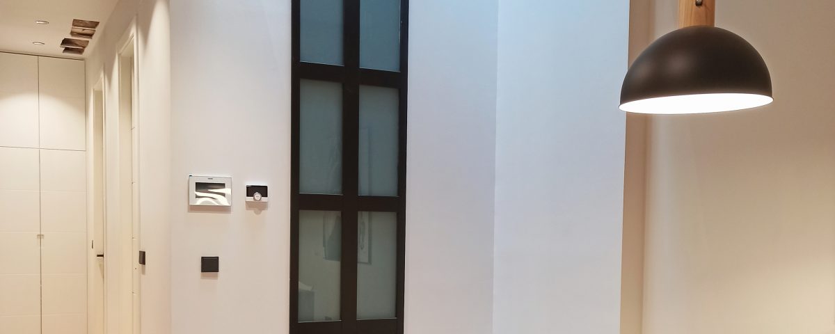 Mesa de madera en un comedor blanco con una lámpara encima