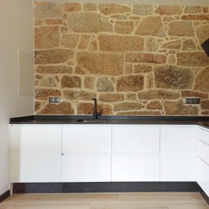 Cocina en blanco y negro con pared de piedra