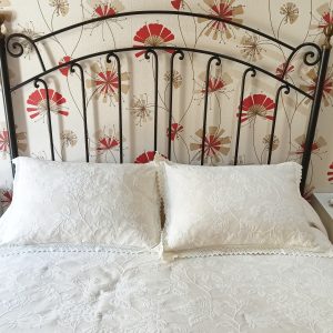 Dormitorio con cabecero de cama de matrimonio negro, cama blanca y mesitas blancas