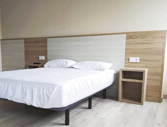 Habitación de hostal con cama de matrimonio y mesitas de noche