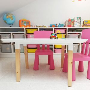 Habitación de juegos para niños, con mesa y sillas y estanterías en blanco