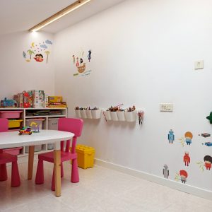 Habitación de juegos para niños, con mesa y sillas y estanterías en blanco